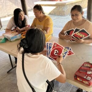Youg girls and their mothers playing giant Uno around a table