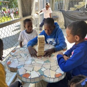 Young children playing Jenga around a table